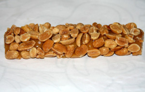 A close-up photo of a PayDay bar, showing the caramel base shrouded in many peanuts.