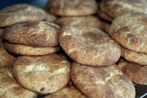 A close-up photo of many snickerdoodle cookies, showing the fine detail of the cinnamon and sugar on the cookie surface.